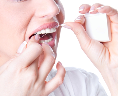 Young woman flossing teeth , studio shot