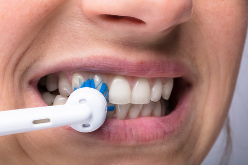 Woman’s Teeth With Electrical Toothbrush